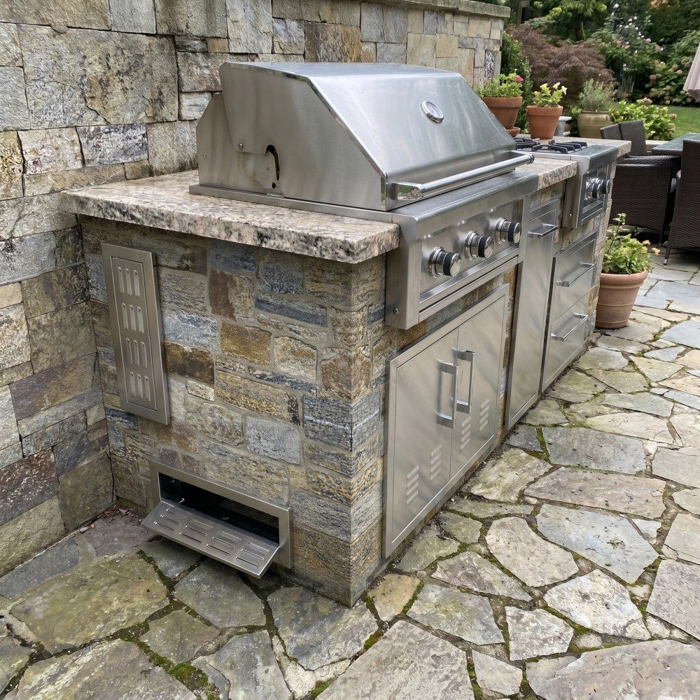 Stone grill island — Built-in grill island with side vent and storage in natural stone.